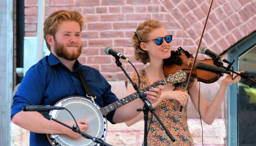 Six young musicians pose with their instruments: keyboard, fiddles, banjo, and acoustic guitar.