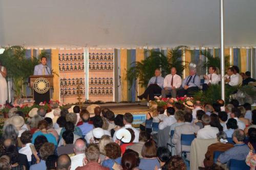 A man speaks at a podium bearing the Smithsonian sunburst logo for a crowd of seated people.