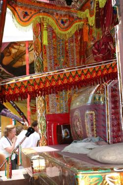 Interior of the decorated truck, with red,  yellow, and orange fringe and tasstle hanging and sparkling striped walls.