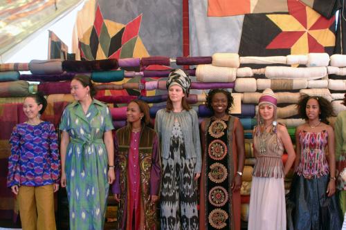 Seven women pose wearing various traditional textiles.