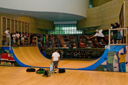 A colorful, painted half-pipe sits inside the Museum of the American Indian. Around and on top of the half-pipe are Native skateboarders, getting ready to show off their tricks.