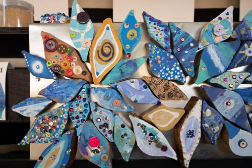 Close-up on several eye-shaped pieces of artwork arranged on a silver surface, radiating outward like a flower.