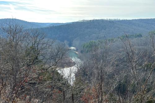 Through bare trees, a view of a river winding through hills.
