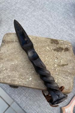 Shucking knife made of dark metal, with a twisted handle design.