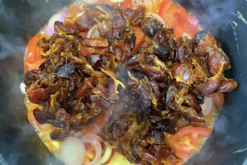 A dish full of barbecue sauce ingredients before they are blended: pitted dates, tomatoes, onions, and more