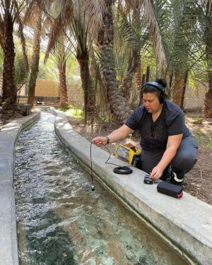 Diana Chester, in all black, dangles a microphone over the water channel.