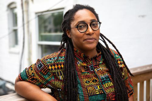 Woman poses outdoors with D.C. rowhouses in background.