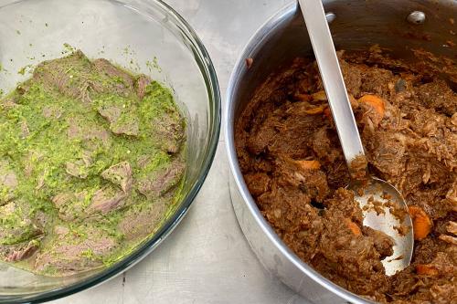 Two large bowls: one filled with meat marinading in a greenish sauce, and one with a finished meat stew, pieces of orange carrot visible, and a large silver serving spoon.