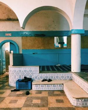 A Turkish bath room with white, arched ceilings, walls that are blue, white, and beige, and tiled floors of the same color palette. 