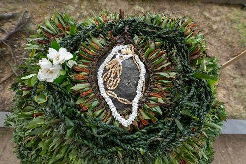 The volcanic pōhaku (rock) Kānepō is adorned with lei, leaves, ropes, shells, and white flowers. 