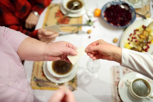 Two people break a consecrated wafer over a table full of food.