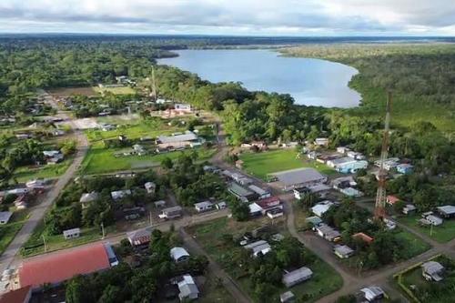 Aerial view of a village amid forested area and adjacent to a lake.
