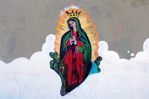Painting of the virgin, set among fluffy white clouds.