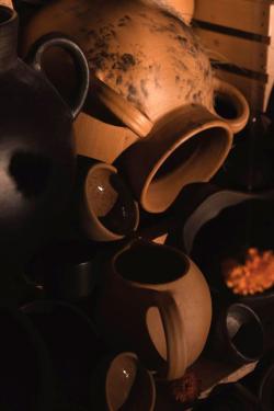 Close-up on a pile of earthen colored veramic jugs, with orange marigolds arranged among them.