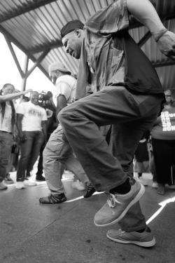 Two men dance for a crowd outside.