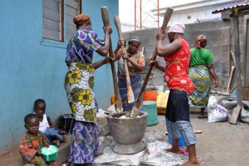 Women work together to pound boiled yam