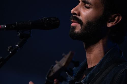 Close-up on a man playing a guitar and singing into a microphone.