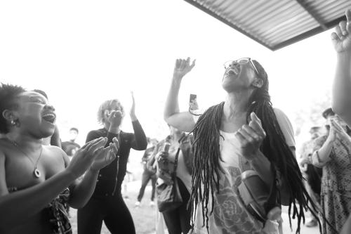 A crowd of people dance outside, laughing or singing.