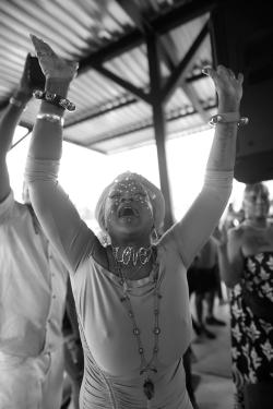 A person wearing a necklace that reads LOVE dances, arms raised in the air.