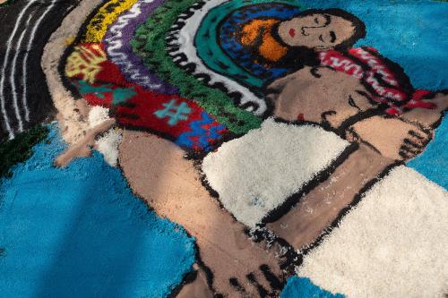 Close up on the Maya woman weaving scene, with a colorful huipil and a loom made out of rice