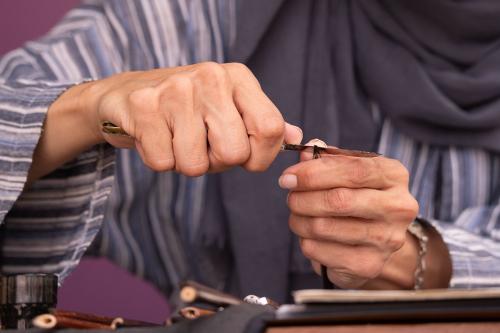 Close-up as a woman shapes the tip of a stylus with a knife.