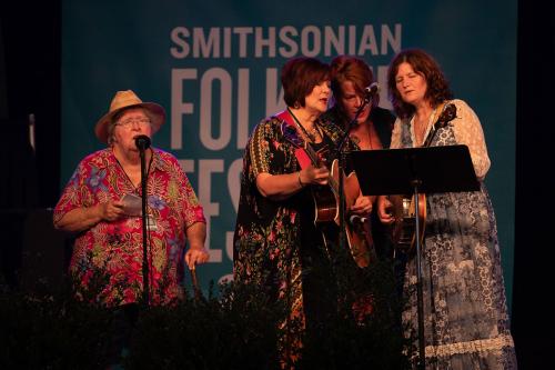Four women on stage singing.