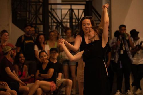 Two women dance in front of a crowd.