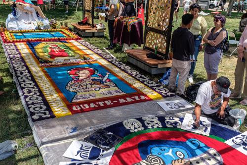View of the Ubaldo Sanchez at work on el Cargador de Tiempo (Carrier of Timer) on the second alfombra, with view of the cofradía and Virgen de Guadalupe behind.