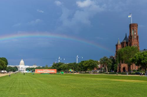 A double rainbow with a view of the Capitol Building, the Smithsonian Folklife Festival trailer, and Smithsonian Castle.