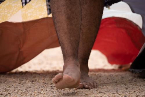 Close-up on the person's bare feet walking on gravel.
