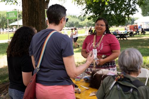A woman behind the table speaks with three visitors.