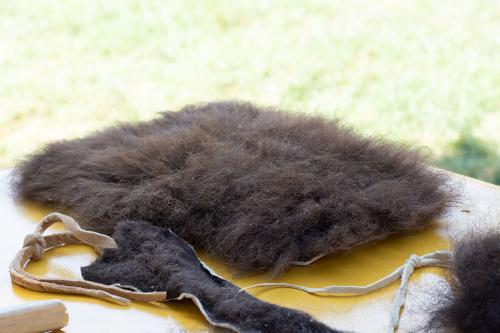 On a yellow tablecloth, pieces of animal hide with dense, dark brown wool.