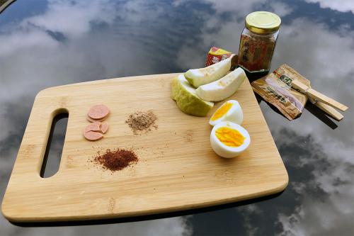 The same cutting board of snacks on a glass table reflecting a cloudy sky. Next to it, a jar, opened foil bag, and container of hawthorne candies.
