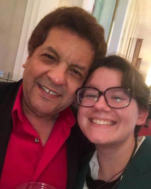 A young adult and man smile while taking a selfie together.