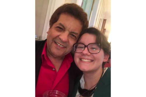 A young adult and man smile while taking a selfie together.