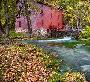 Red barn on a creek in the woods.