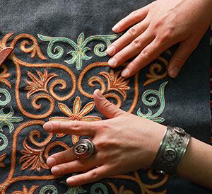 two hands touching embroidery.