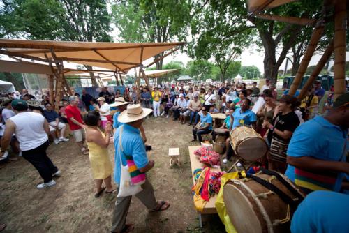 Visitors and artists under the guadua (bamboo) tents in the Colombia program area.