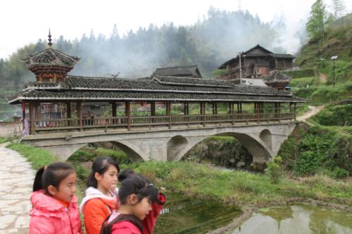 The “Wind and Rain” covered wooden bridge in Dimen is a characteristic Dong village architectural feature, typically with built-in resting spots at either end. A few minutes earlier the three girls were afraid of me, then their curiosity preva