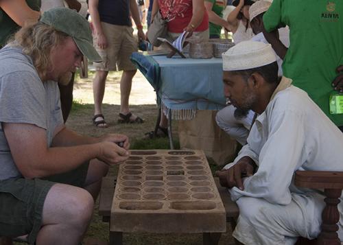 Ali Abdalla Skanda and a visitor play mancala on a hand-carved board.