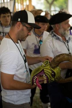 The Basque Joaldunak and the California Grupo Nuu Yuku, both traditional parade groups, met for this first time this morning to discuss potential collaboration. The Joaldunak presenter, Unai Bereau, examined one of the diablos masks. Photo by Pruitt Allen