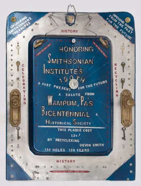 A handmade blue and silver sheet-metal plaque inscribed with words and phrases to commemorate the 150th anniversary of the Smithsonian and decorated with a variety of metal screws, keys, and two gold doorknob plates.