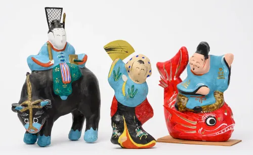 Three Japanese figurines made of painted papier-mâché in different action poses.