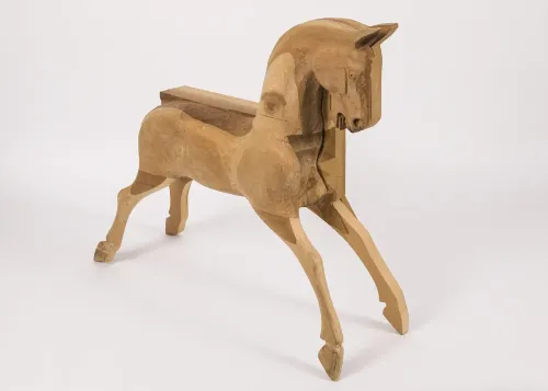 An unfinished rocking horse carved from light blond wood, its legs extended outward to both front and back.