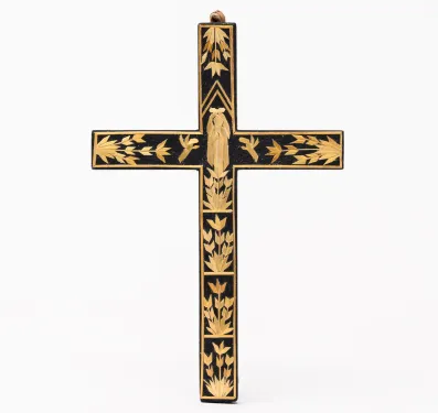 A dark brown wood cross decorated with appliqued straw designs.